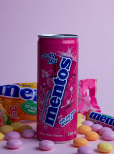 Lata de mentos con fondo rosa rodeada de mentos
